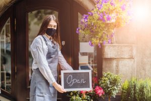 Woman in apron holding open sign